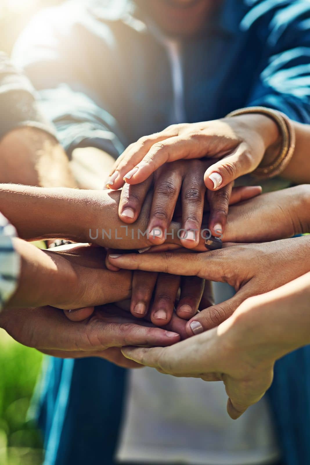 Good friends always stick together. Closeup shot of an unrecognizable group of people joining their hands in a huddle outdoors. by YuriArcurs