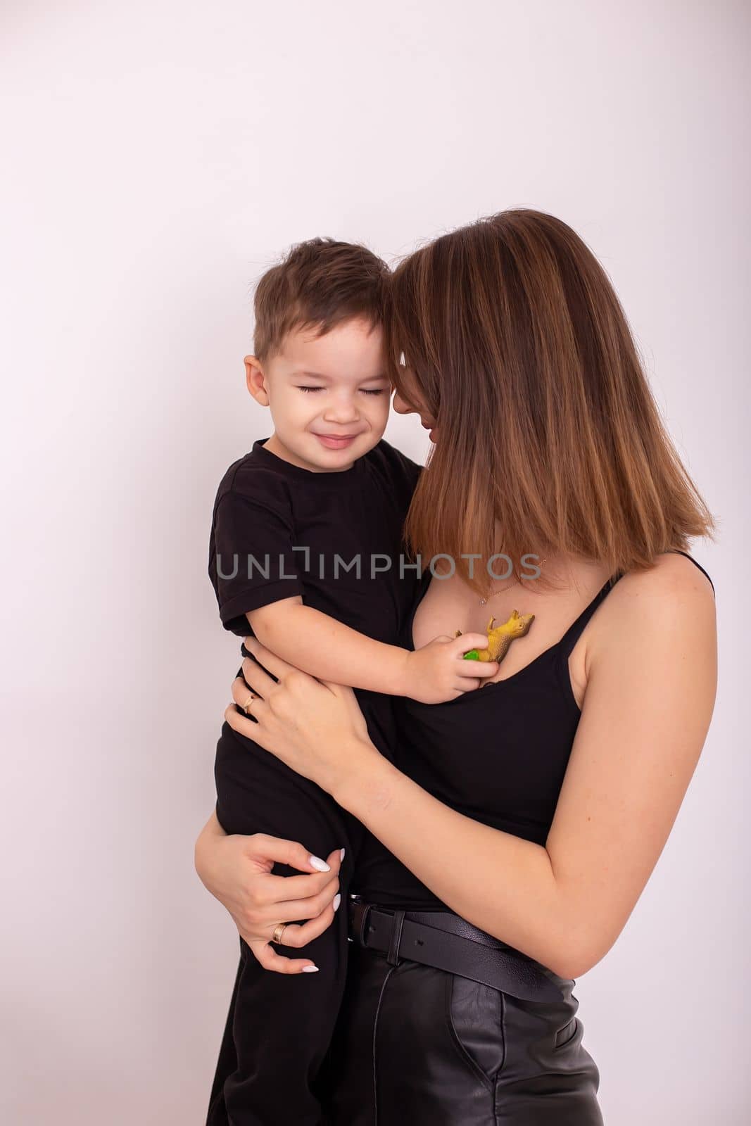 A happy mother is holding a little boy, in black clothes, close eyes. Vertical . Copy space