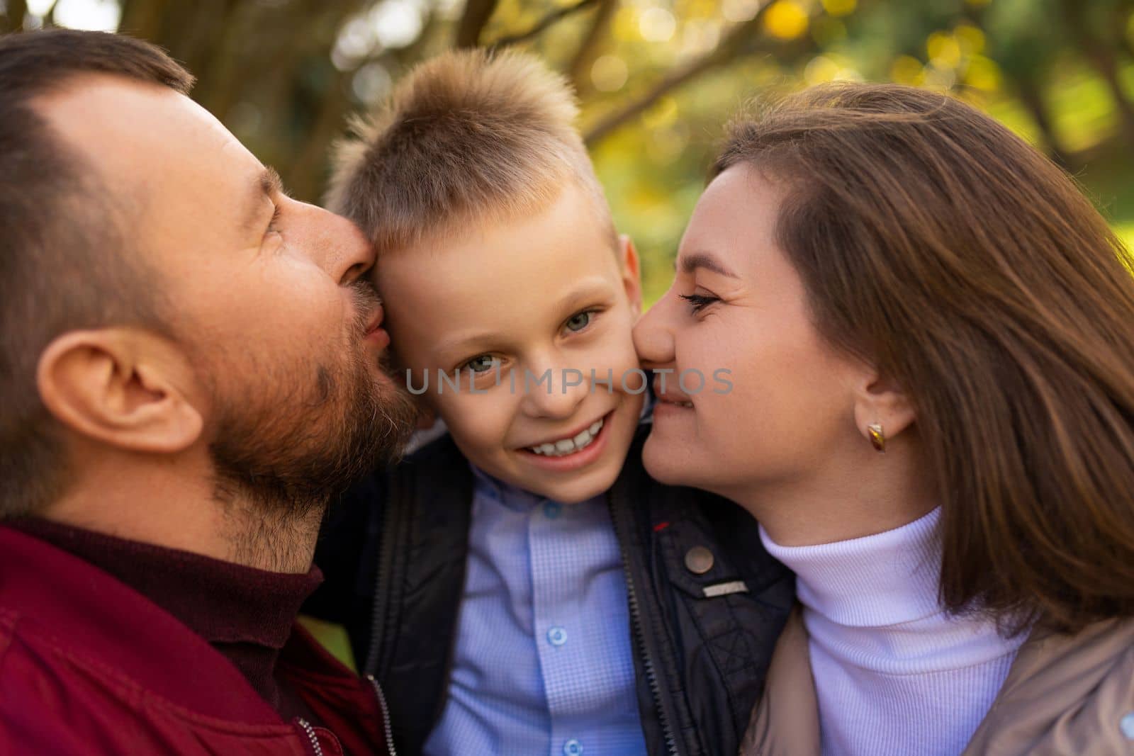mom and dad kissing a child boy between themselves, close-up portrait.