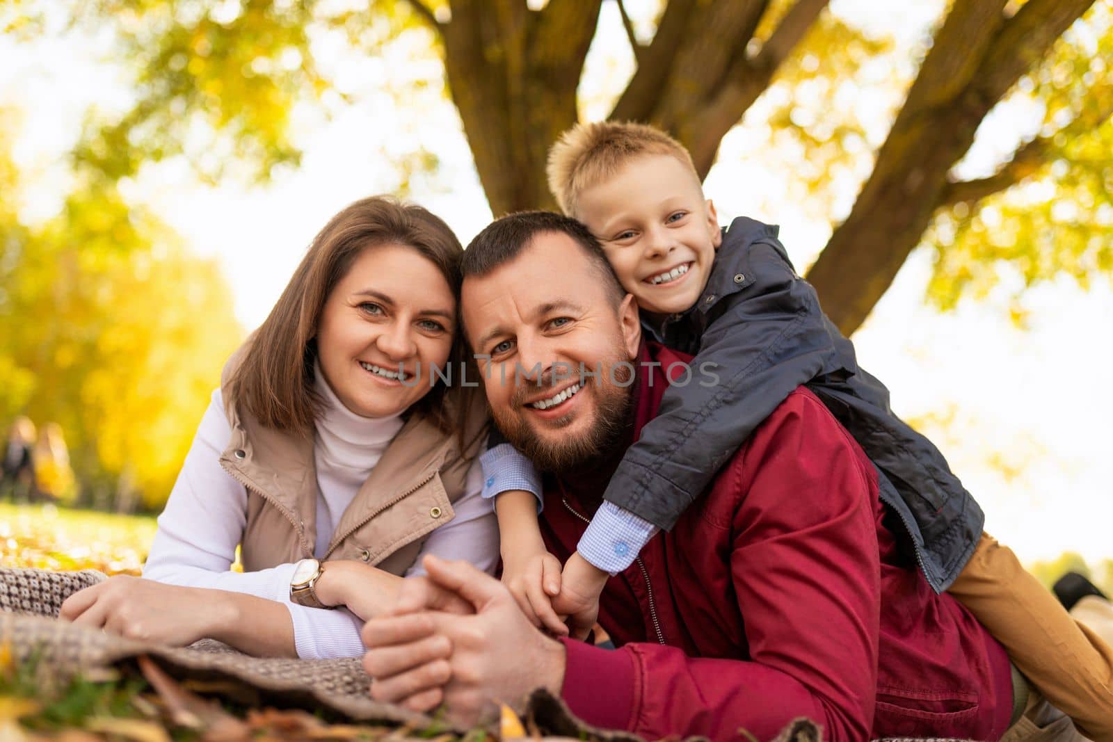 close-up portrait of a happy traditional family with a small child in a park on the ground by TRMK