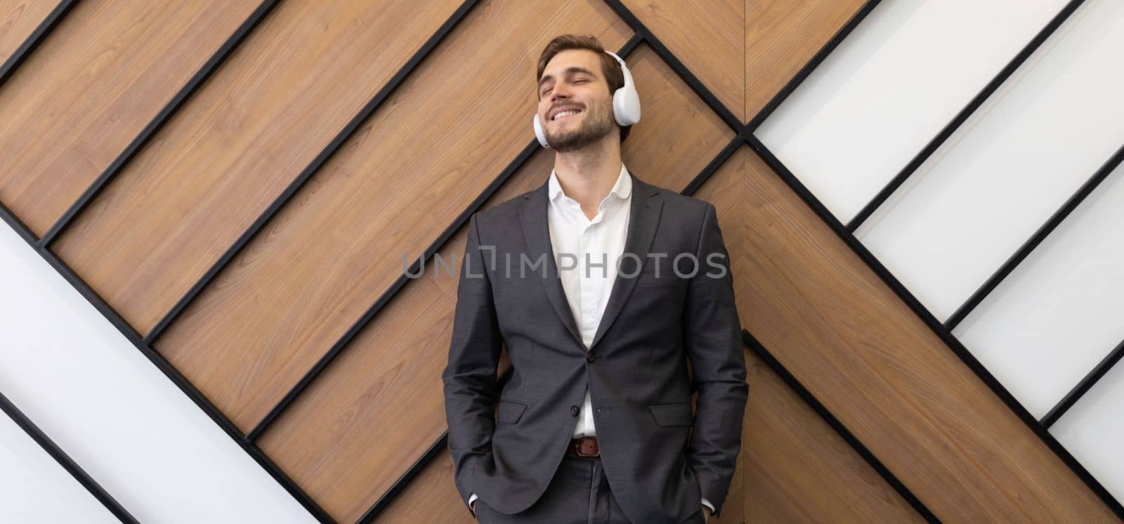 satisfied businessman in business suit listening to music with headphones with pleasure.