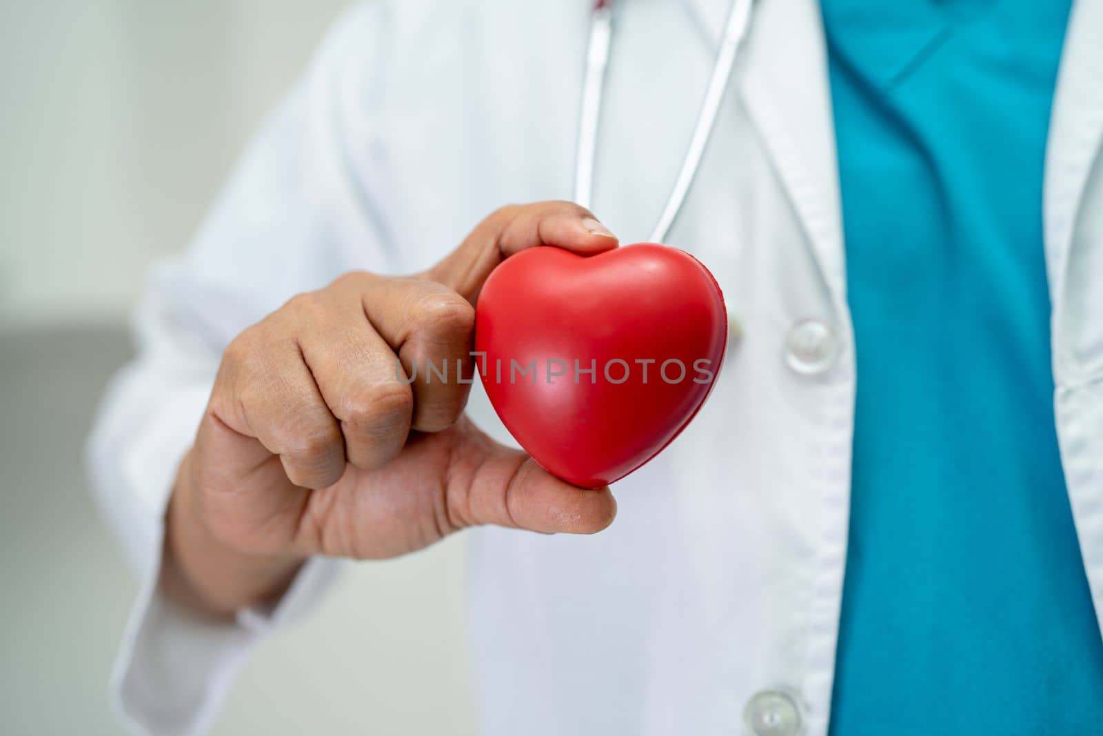 Doctor holding a red heart in hospital ward, healthy strong medical concept.