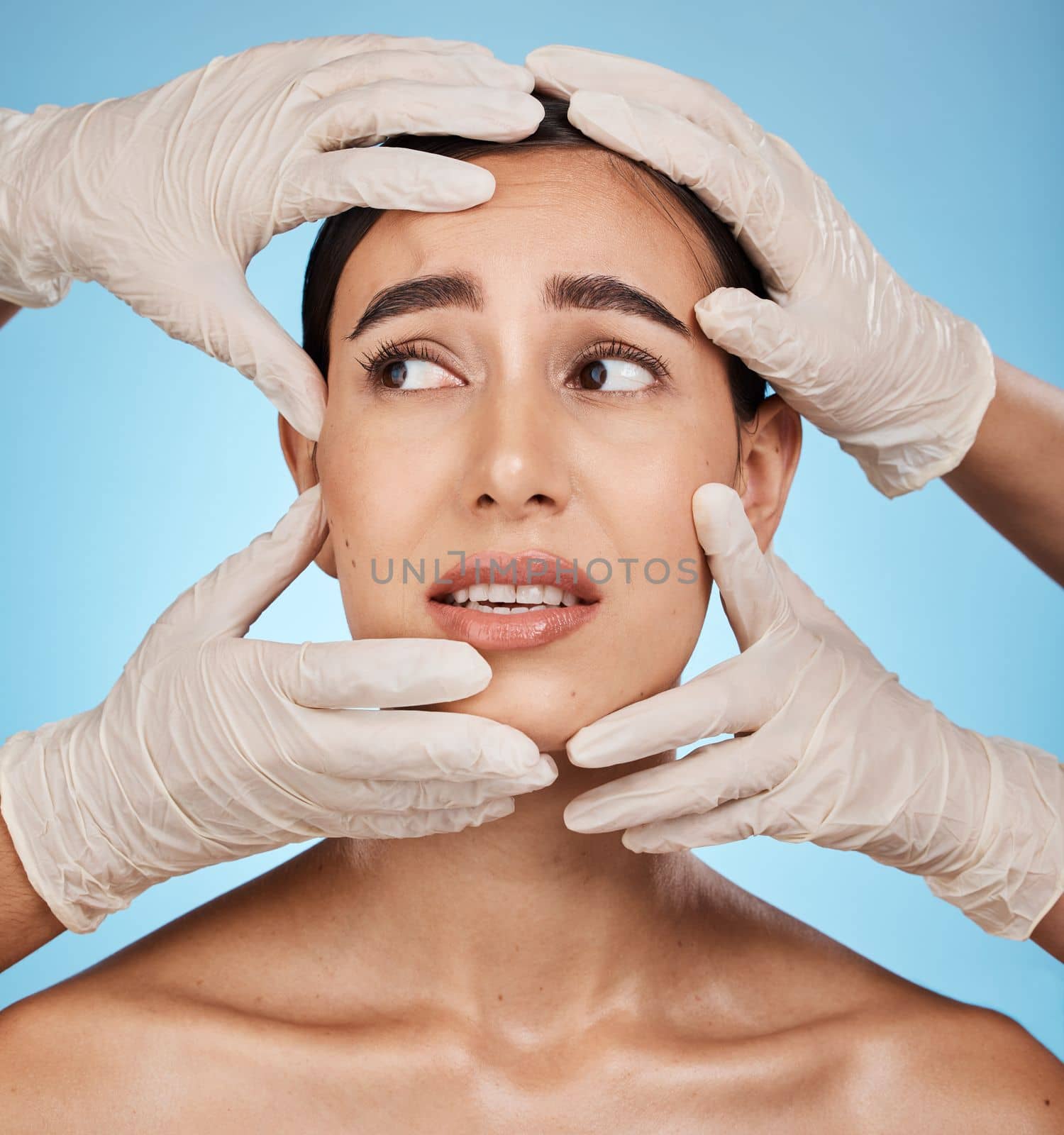 Hands, woman face and plastic surgery, skincare or treatment against a blue studio background. Hand and gloves touching female in medical botox, aesthetic change or liposuction for facial implants.