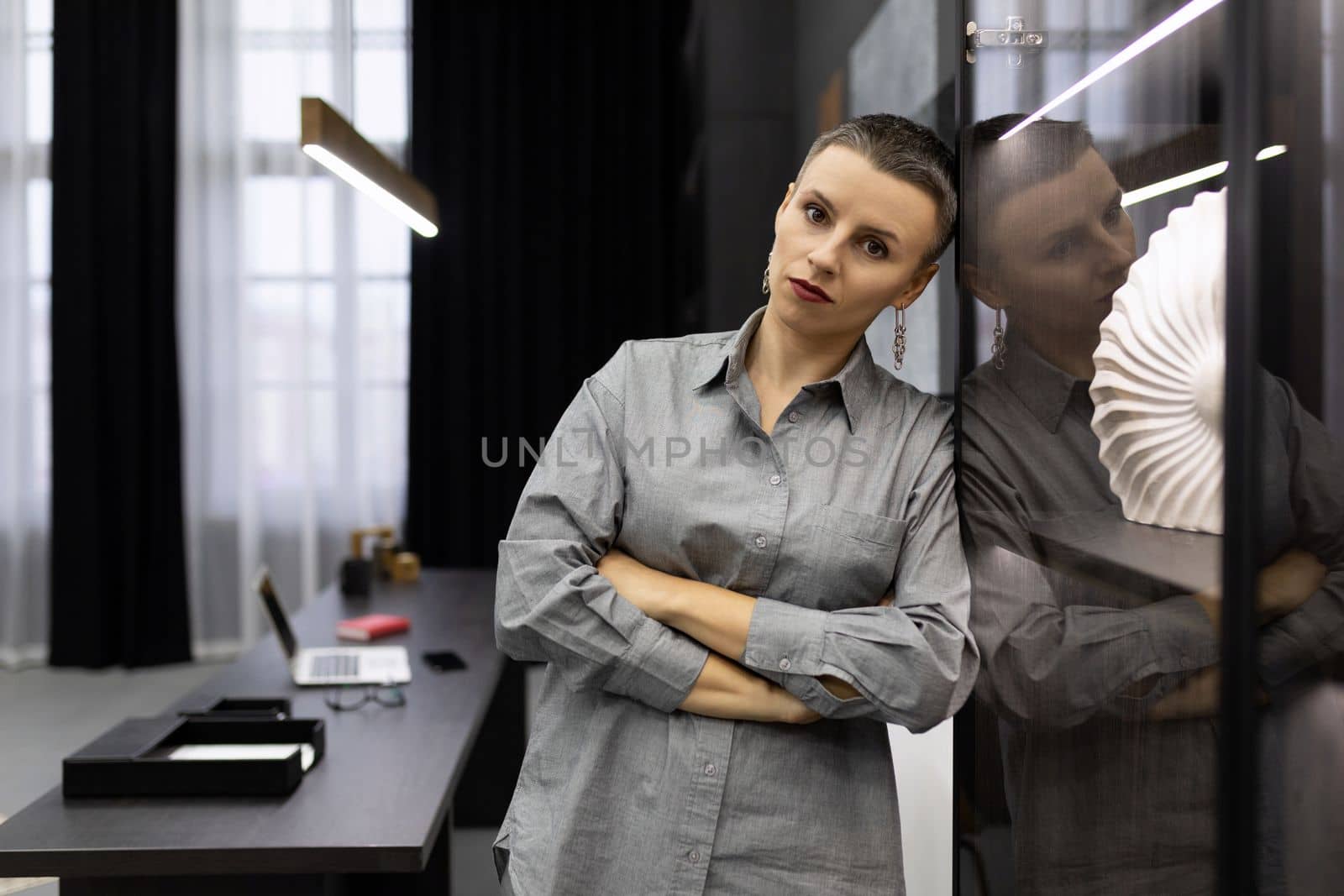 tired serious woman head stands leaning against the wall in the office.