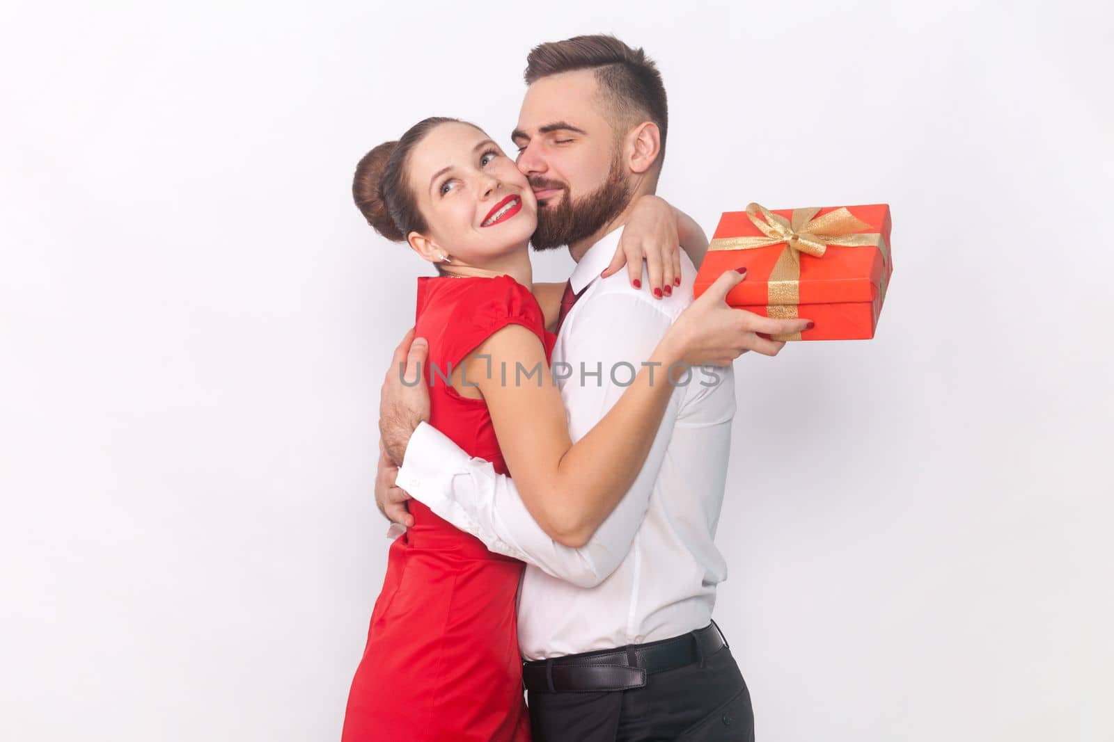 Woman and man hugging each other, female holding red present box, husband kissing his wife. by Khosro1
