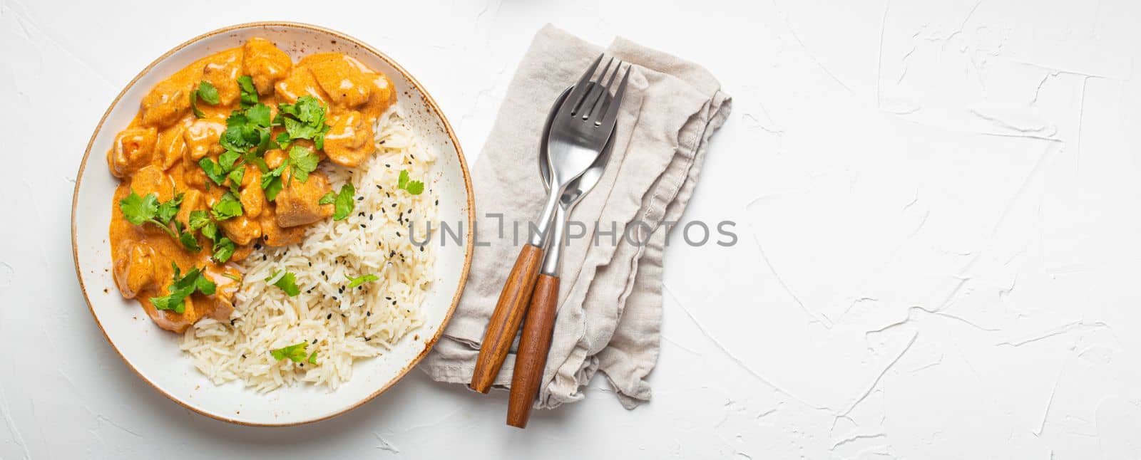Traditional Indian dish chicken curry with basmati rice and fresh cilantro on rustic white plate on white concrete table background from above. Indian dinner meal, space for text by its_al_dente