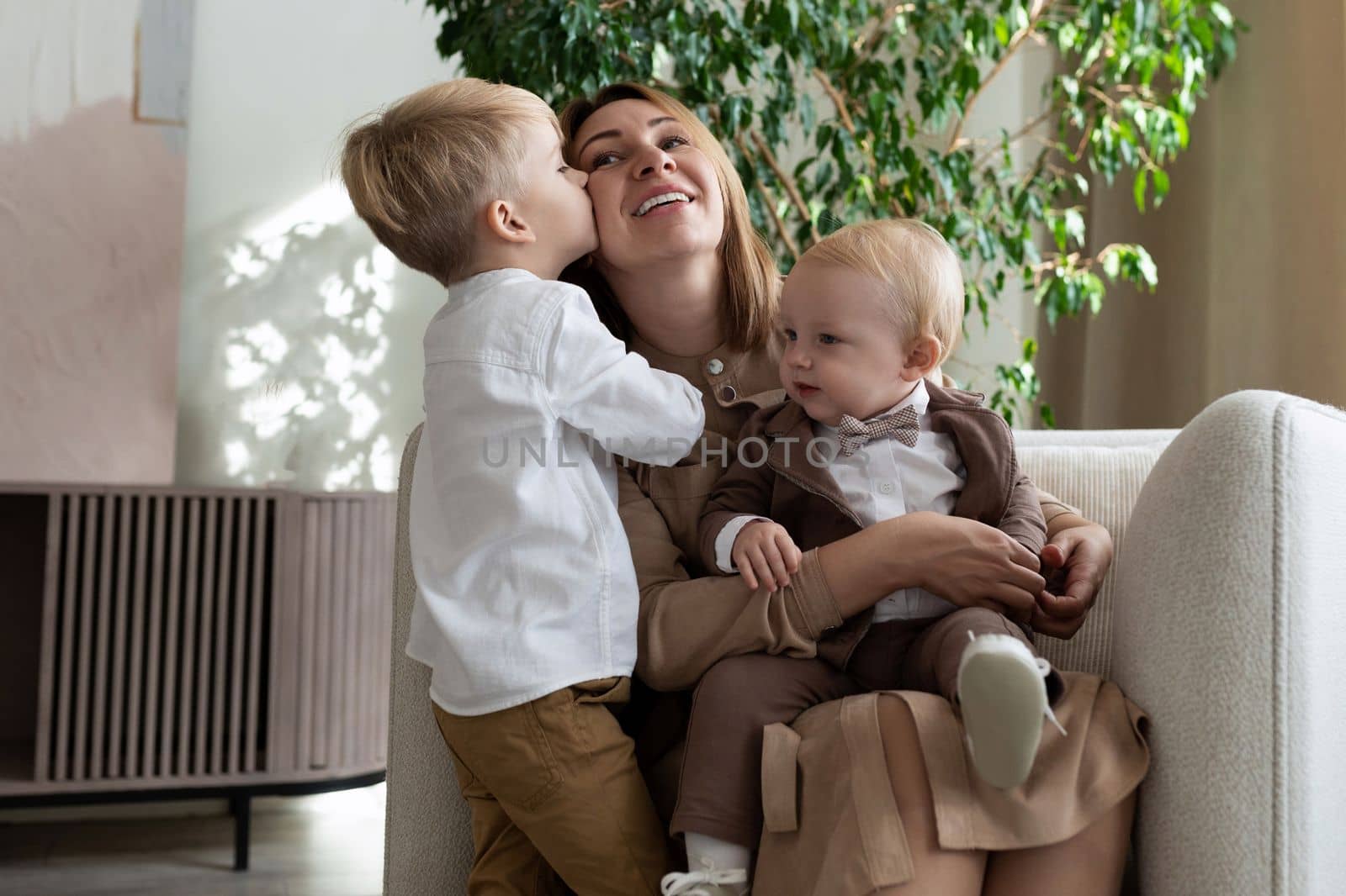 mom with two adorable sons one of whom kisses her on the cheek, mother's day concept.