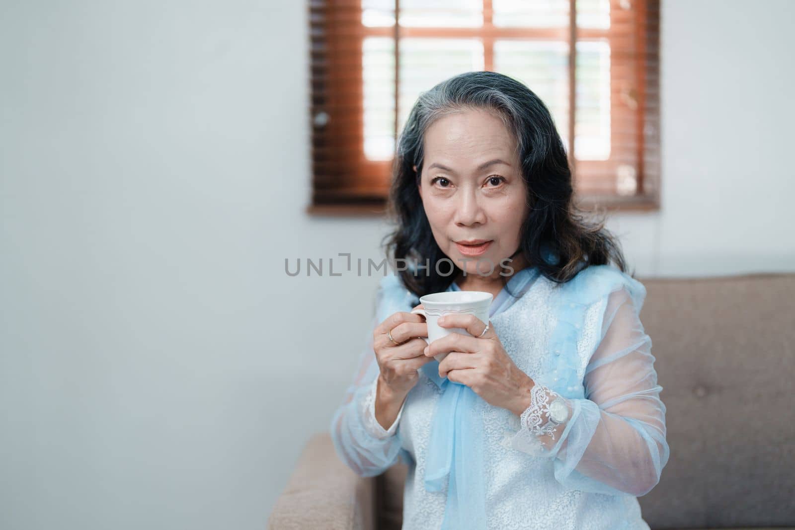 Portrait of an elderly Asian woman drinking tea for health. by Manastrong