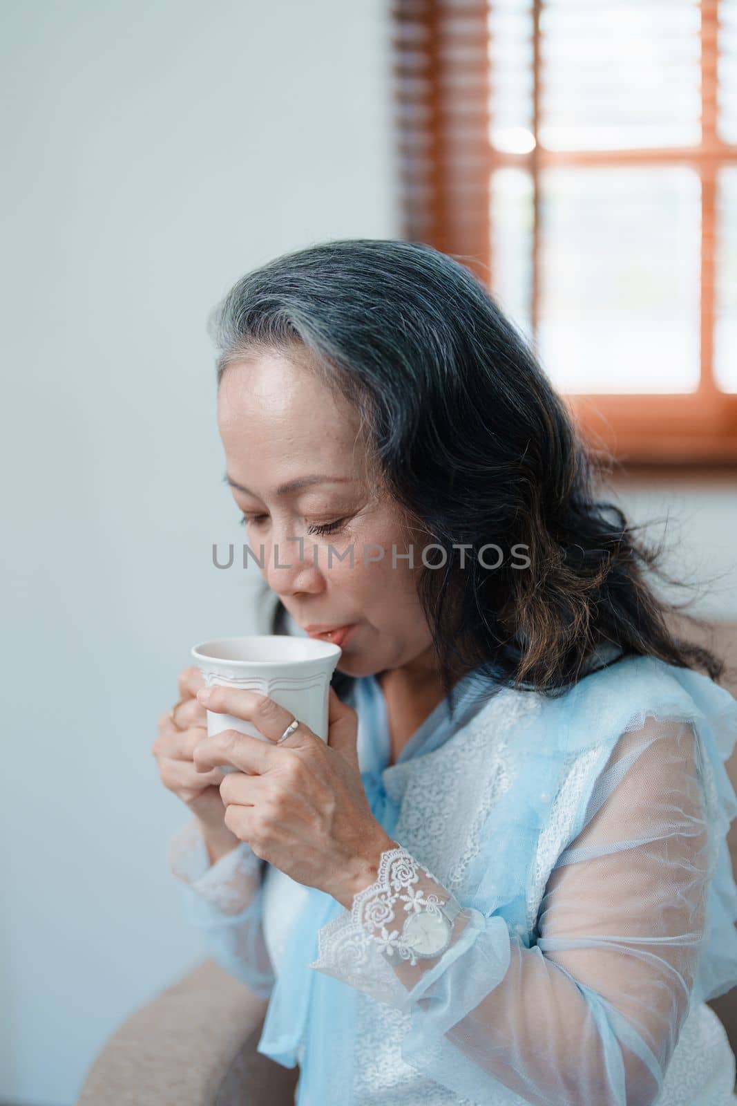 Portrait of an elderly Asian woman drinking tea for health. by Manastrong