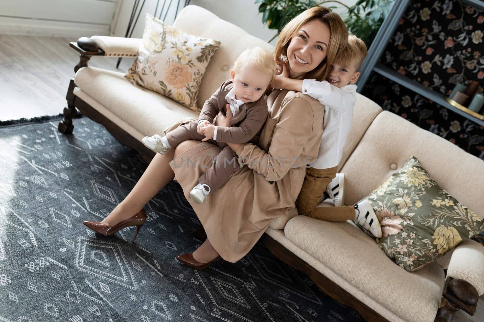portrait of a young mother with two cute sons sitting on the sofa by TRMK