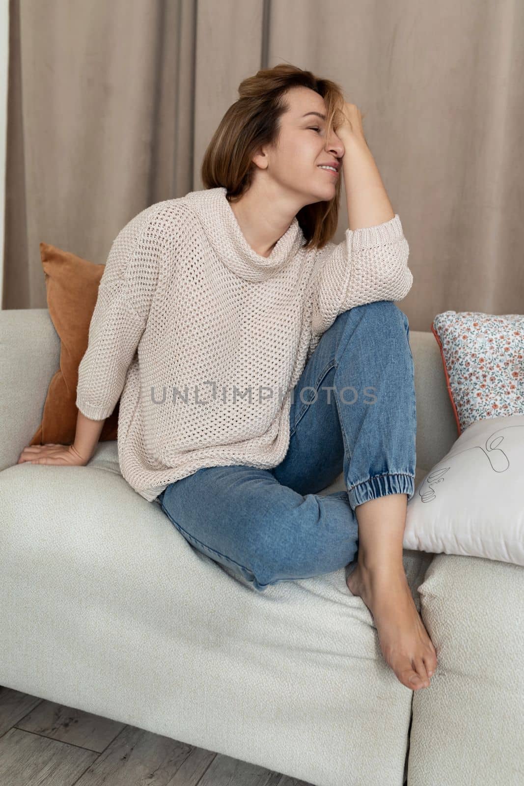 stylish confident middle-aged woman sitting and laughing on the couch.