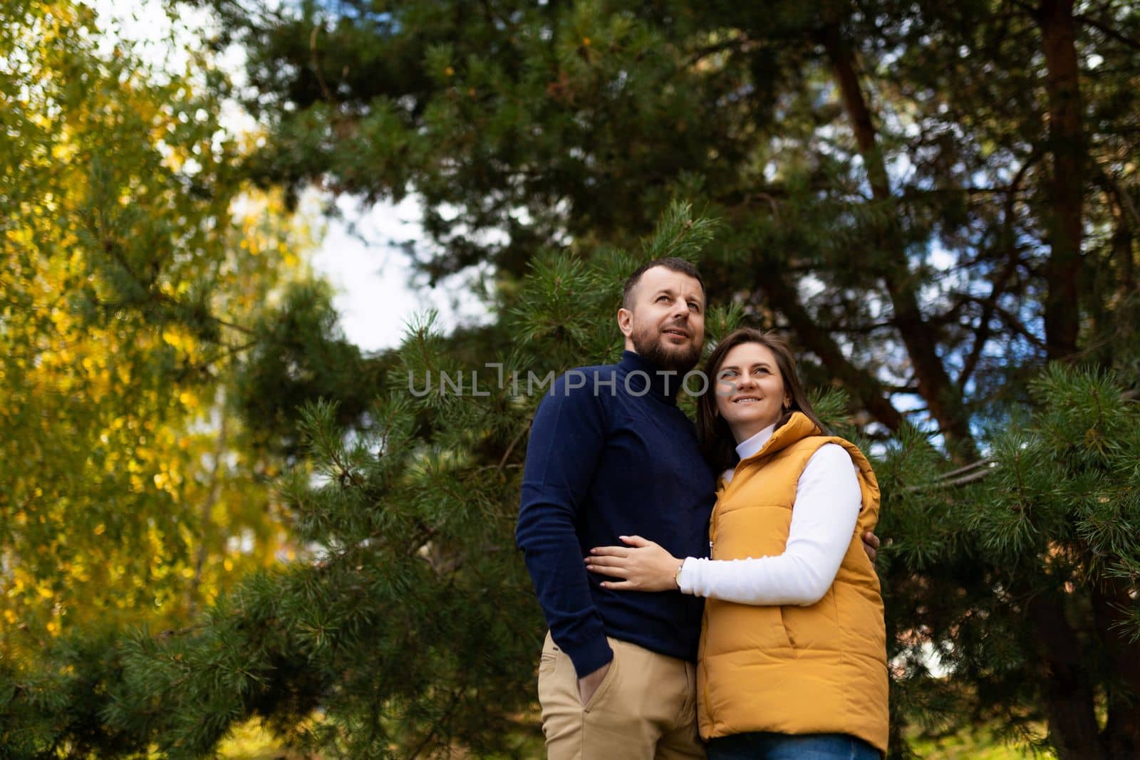 happy married couple hugging in autumn forest by TRMK