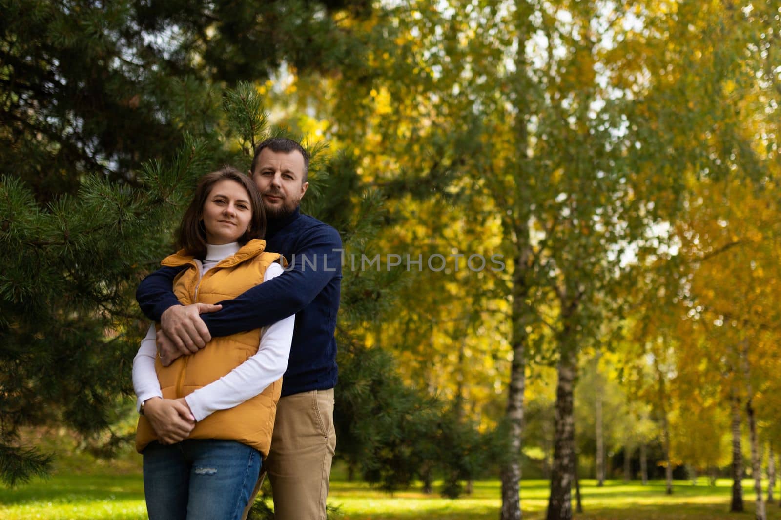 happy adult family traditional couple in autumn forest stands embracing.
