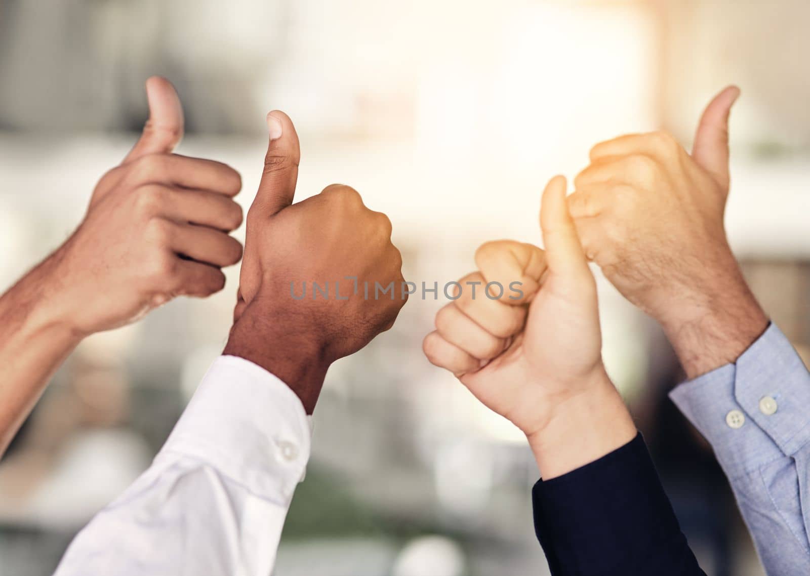 We couldnt agree more. Closeup shot of a group of unidentifiable businesspeople showing thumbs up in an office. by YuriArcurs