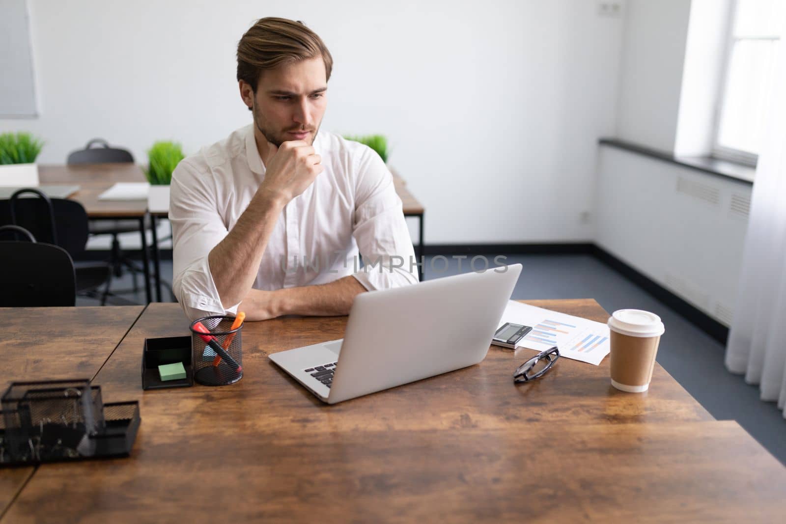 tired businessman filling out tax return on laptop in stylish office.