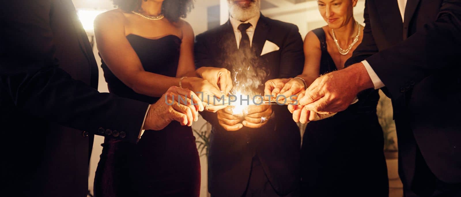 Fire, sparklers and people at a luxury party, event or celebration for new year with formal outfit. Celebrate, matches and group of friends in classy clothes at a black tie gala, banquet or dinner