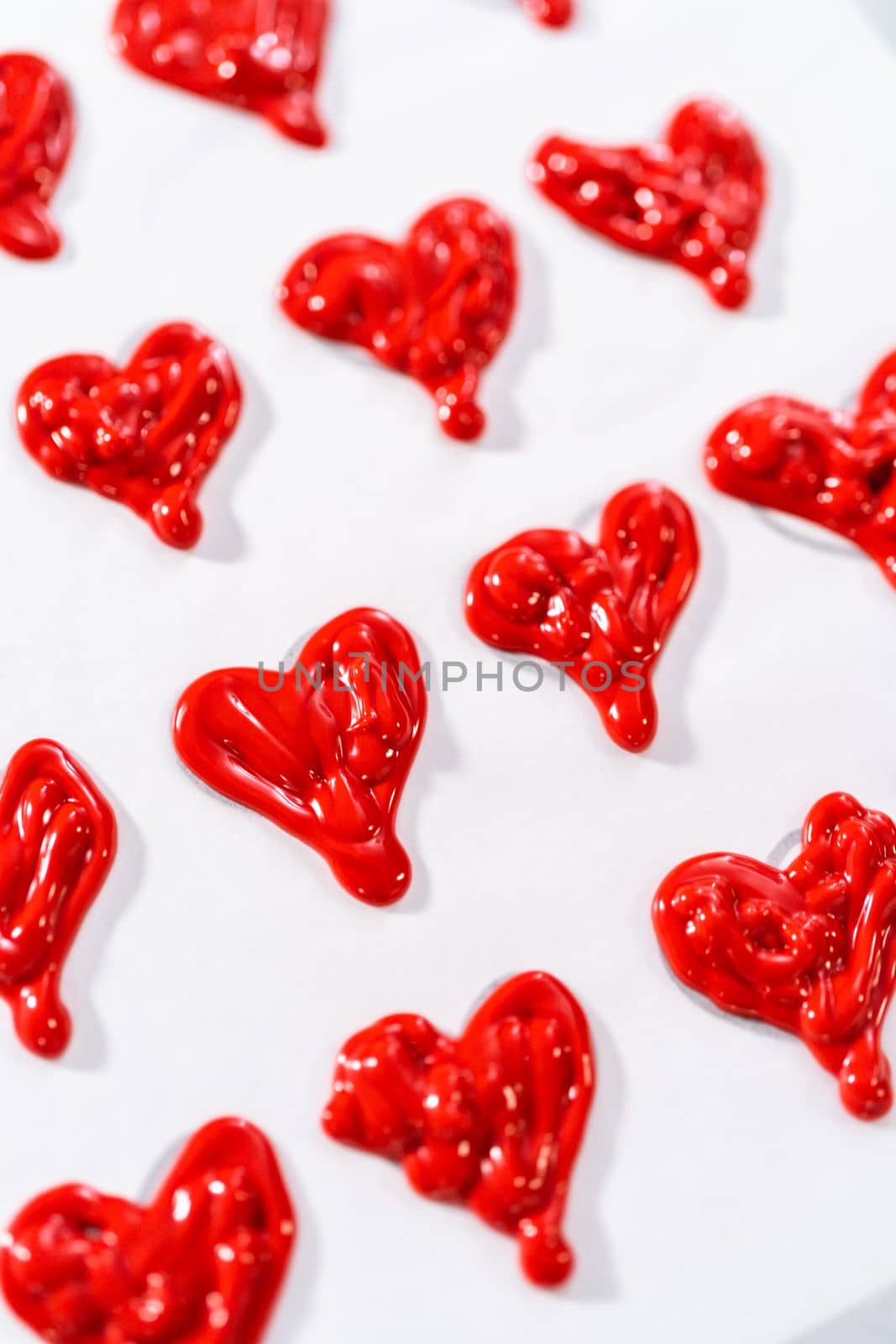 Piping melted chocolate from piping back over the parchment paper to make a chocolate heart.