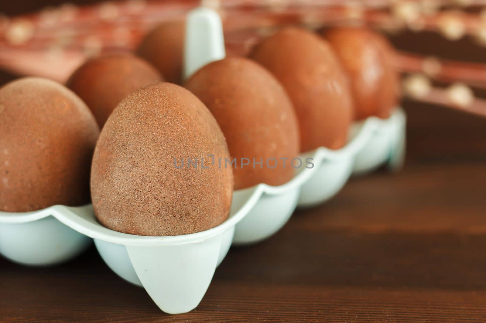 colored eggs in a container on a wooden table. Easter celebration.