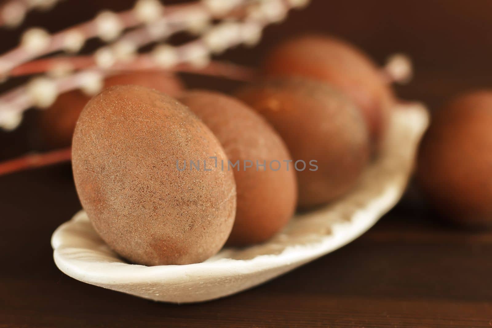 painted eggs on a plate with a sprig of willow on a wooden table. Easter celebration.