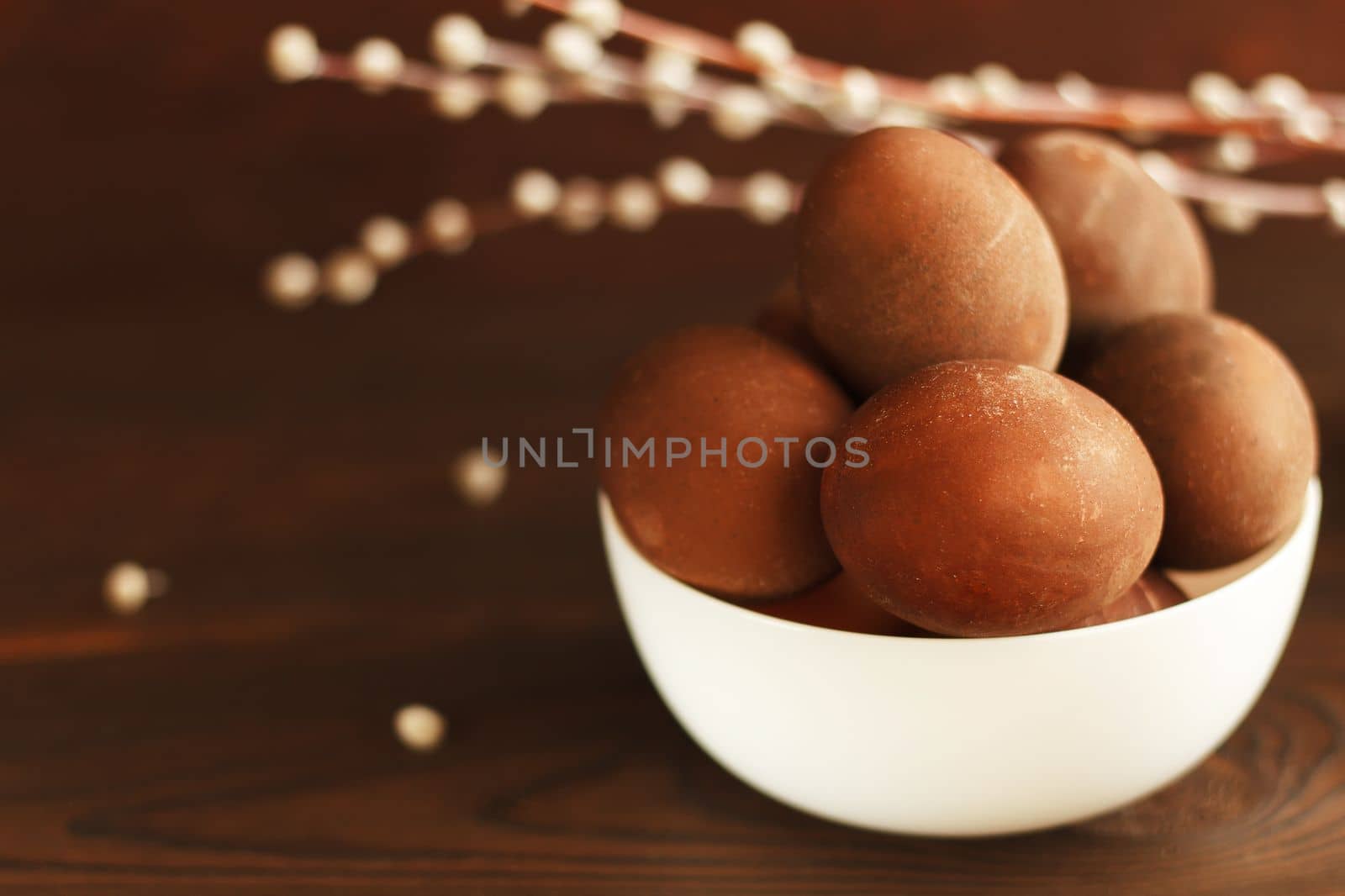 painted eggs on a plate with a sprig of willow on a wooden table. Easter celebration. copy space