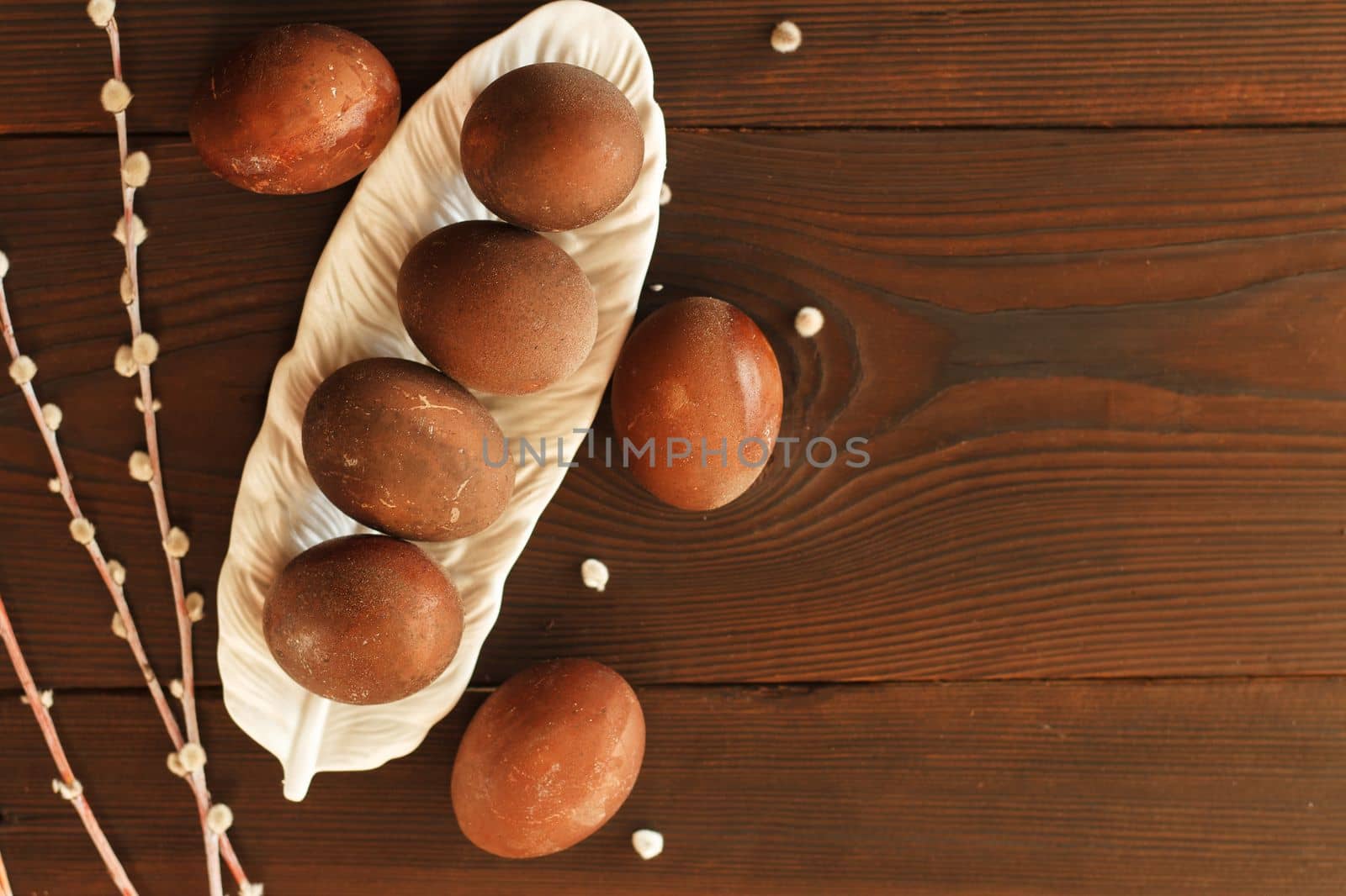 painted eggs on a plate with a sprig of willow on a wooden table. Easter celebration. copy space