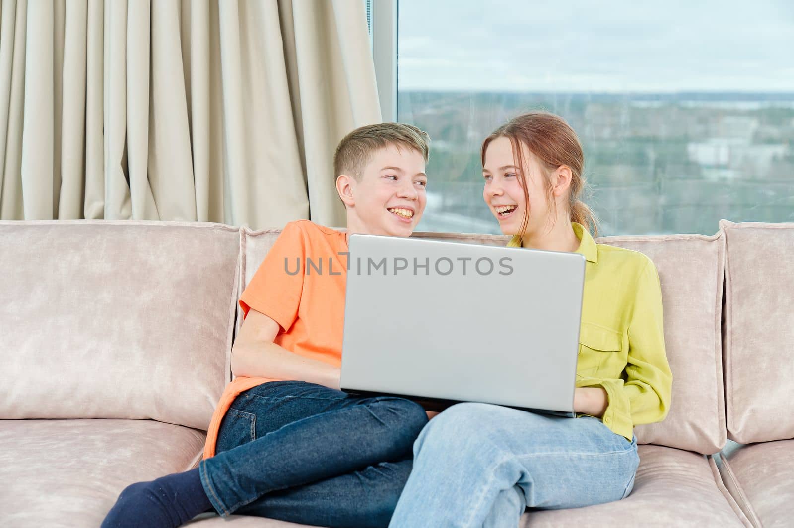 Happy kids on couch using gadget. Watching something online on computer together with family. Rest at home.