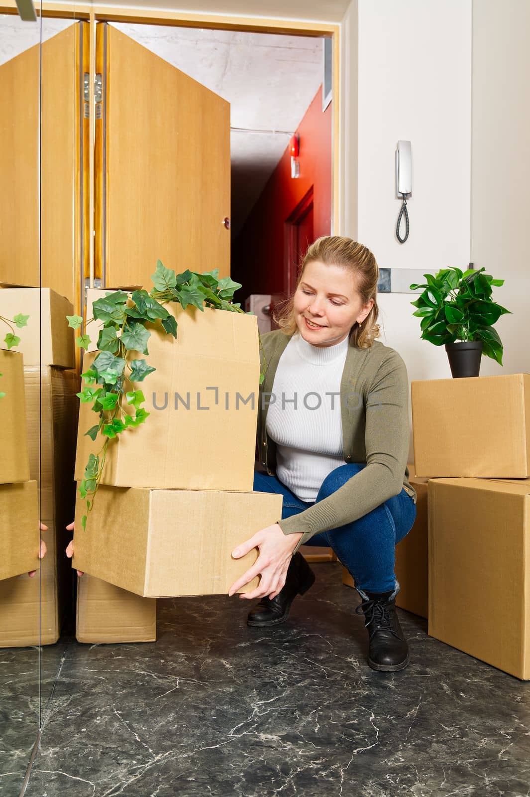 Happy young single woman moving to new home. Having fun in moving day. Woman carrying moving boxes. by PhotoTime