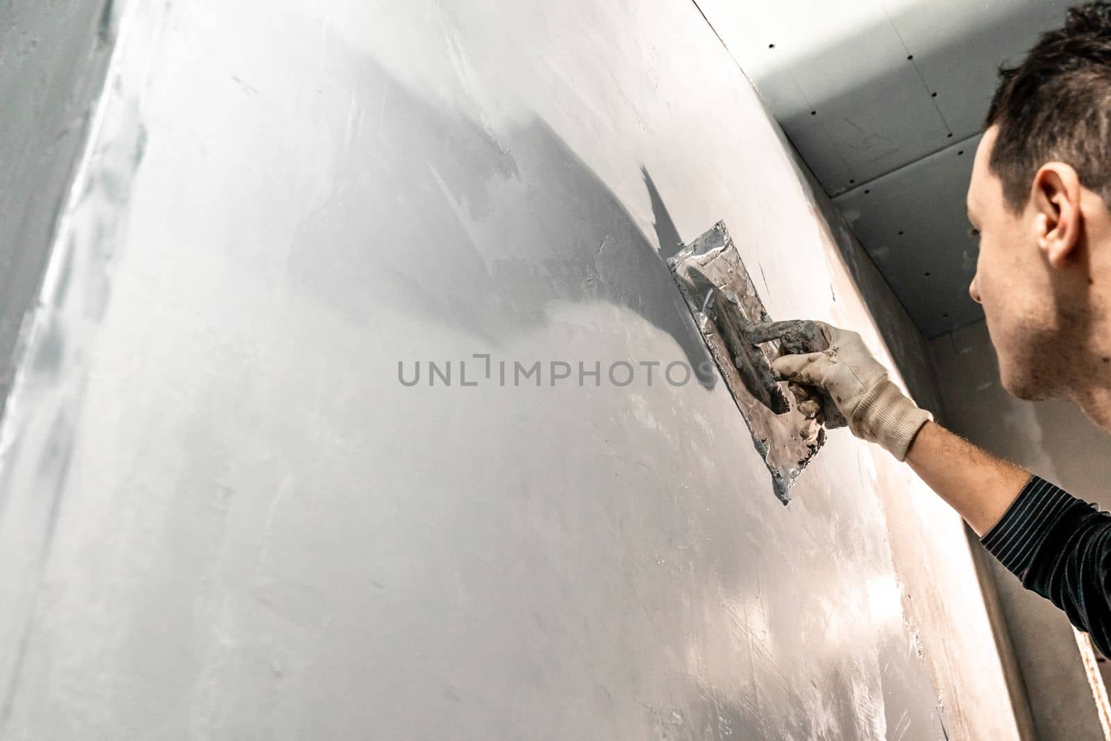 man applies insulation to a bathroom wall by Edophoto