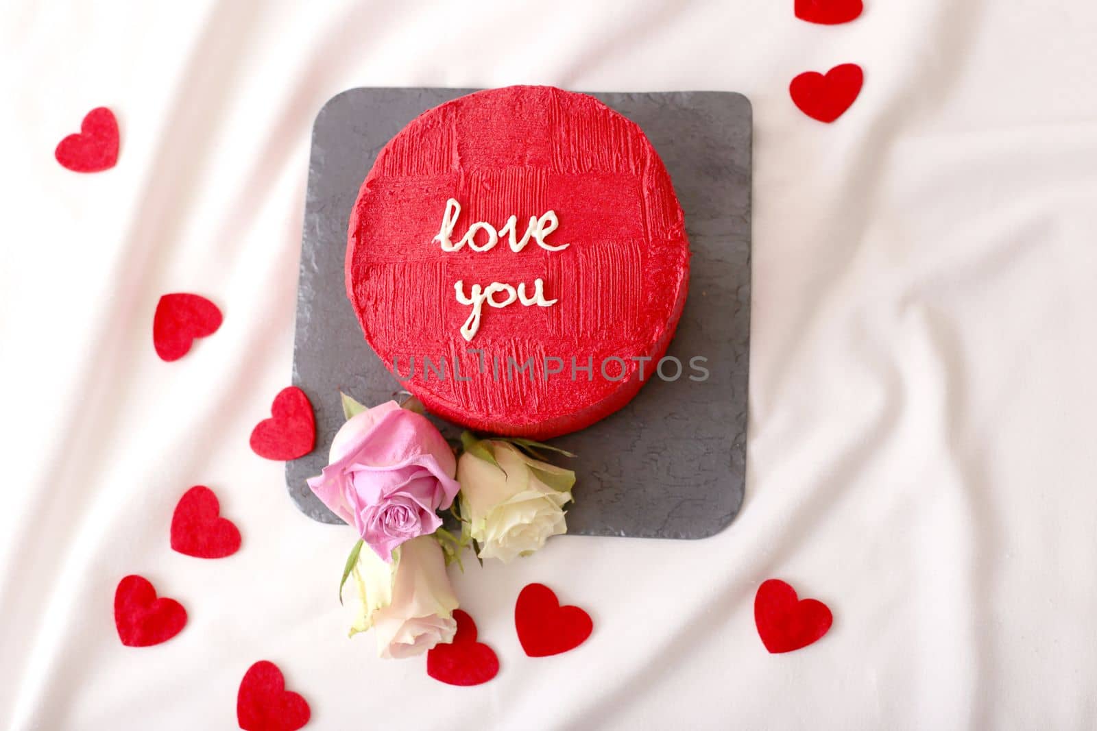 tasty red bento cake, hearts and roses lie on white bed by Zakharova
