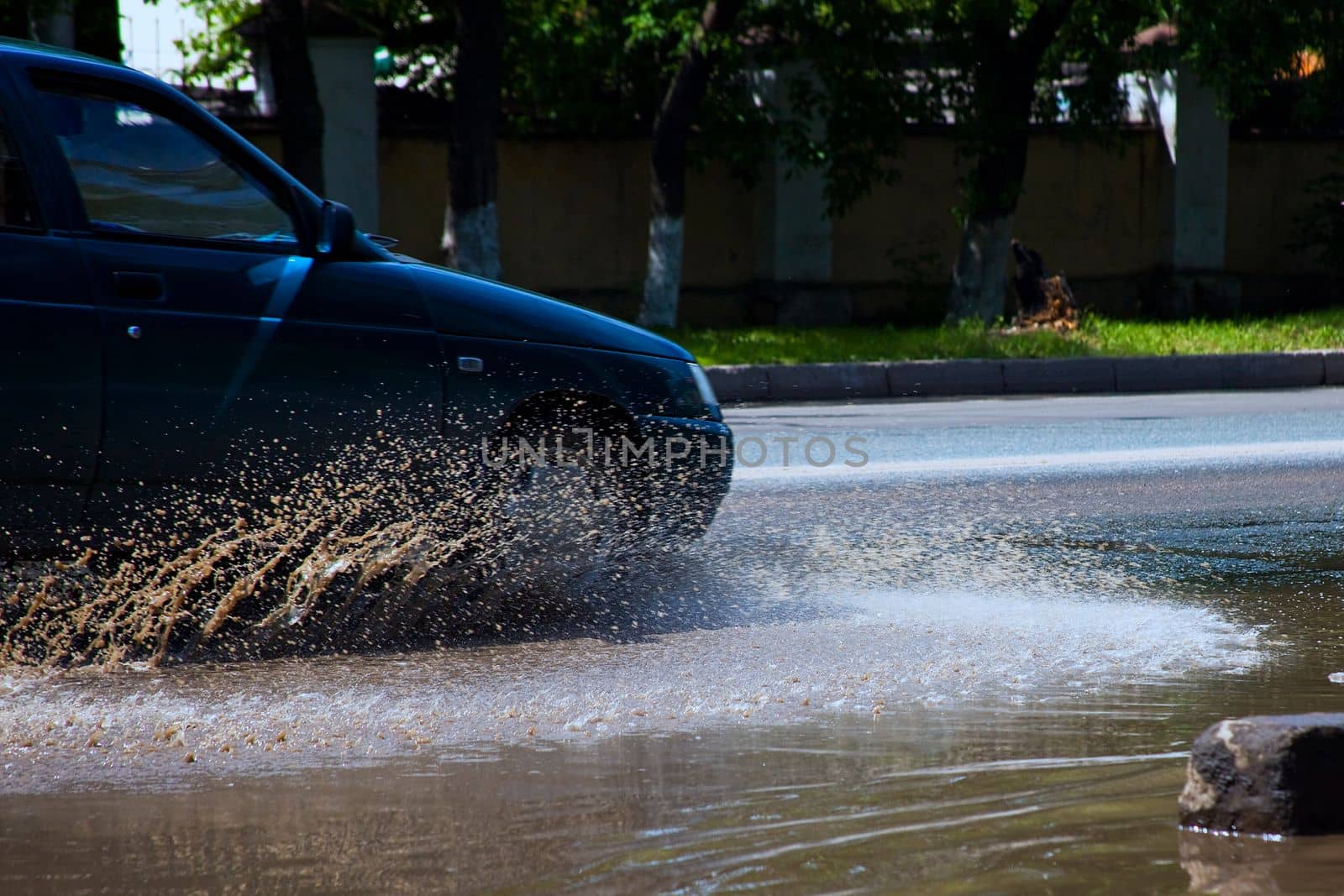 Car drive in dirty puddle on street after rain