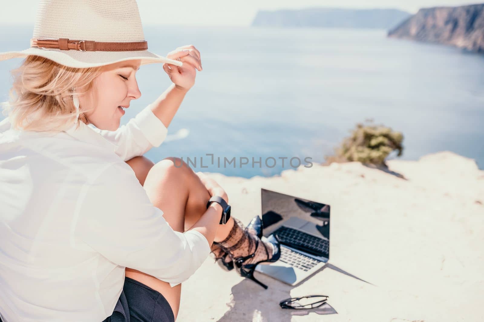 Happy girl doing yoga with laptop working at the beach. beautiful and calm business woman sitting with a laptop in a summer cafe in the lotus position meditating and relaxing. freelance girl remote work beach paradise