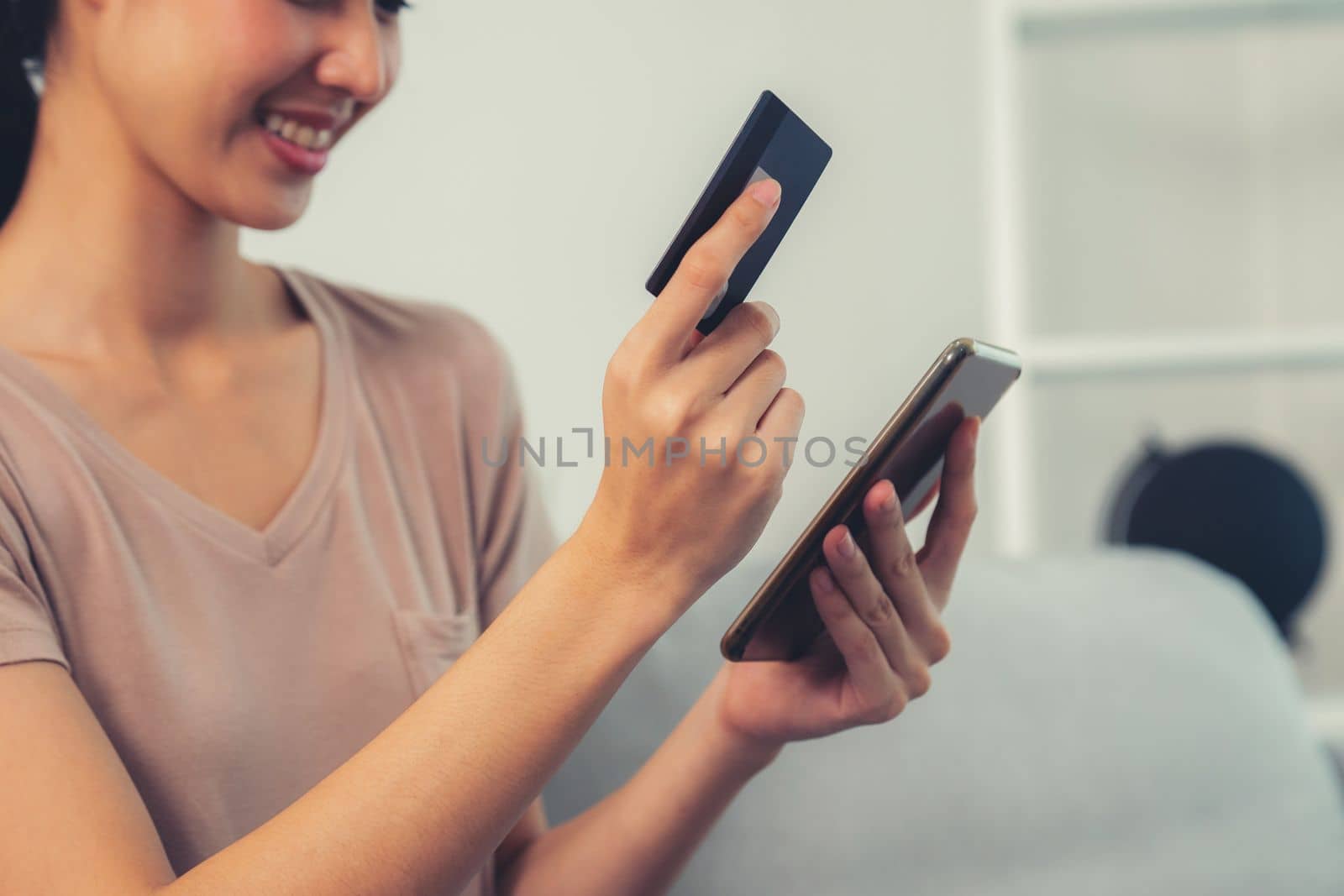 Contented young woman eagerly makes an online purchase using her smartphone. E-commerce business, online purchasing.