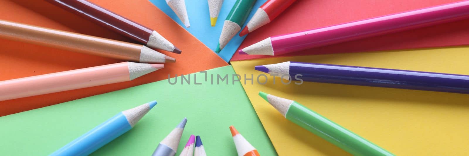 Multi-colored pencils on colored paper on table. Selection of colors and shades in painting concept