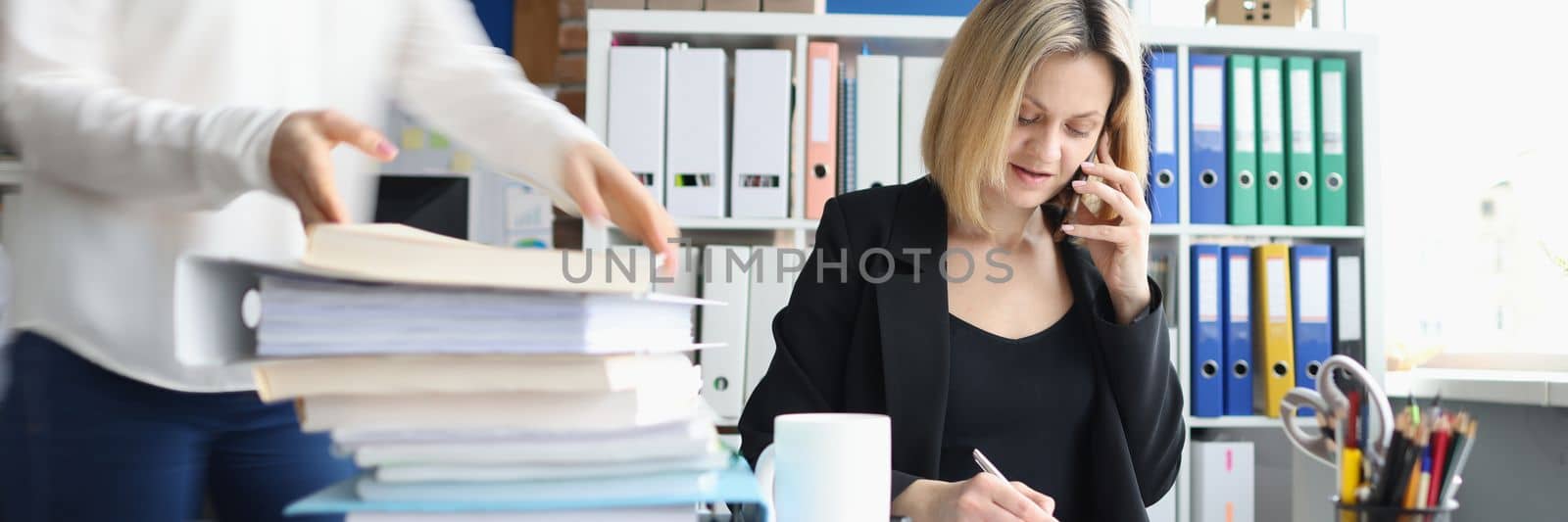 Businessman talking on phone secretary taking documents in office. Working atmosphere in office concept