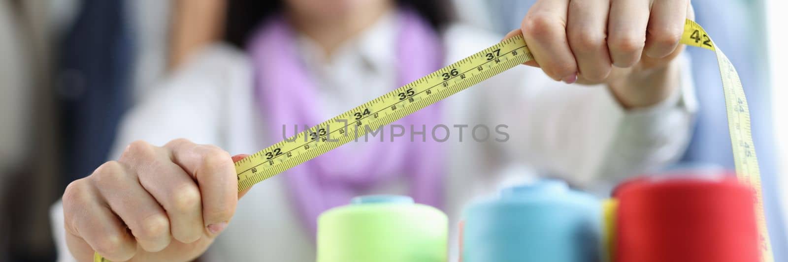 Seamstress holds tape measure in sewing workshop by kuprevich