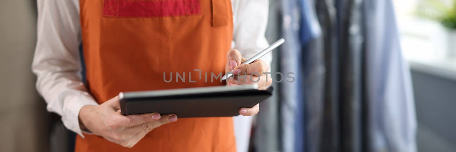 Dry cleaning administrator holds tablet with documents to sign. Laundry service concept