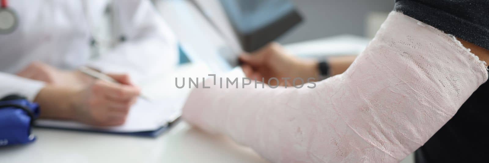 Doctor conducts medical consultation with patient with cast on arm. Hand fracture and treatment concept