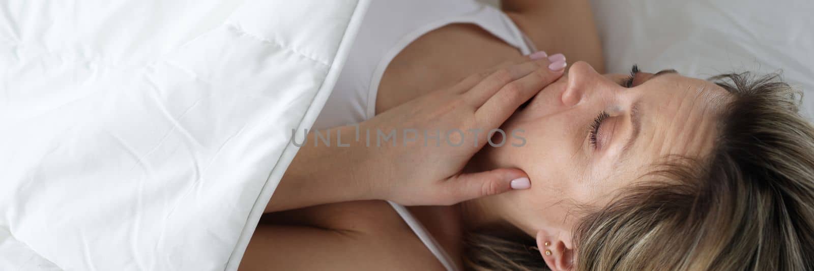 Woman looks in shock under covers in bed by kuprevich