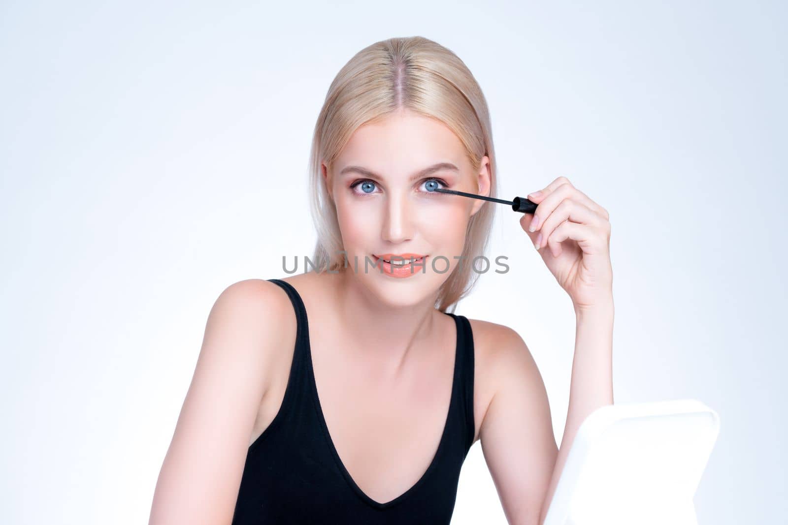 Closeup personable beautiful woman putting alluring black mascara eyelashes. by biancoblue