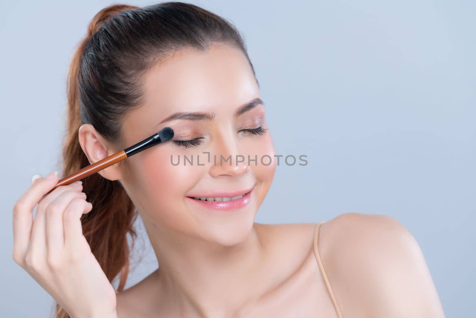 Closeup beautiful girl with flawless applying glamorous eye shadow makeup. by biancoblue