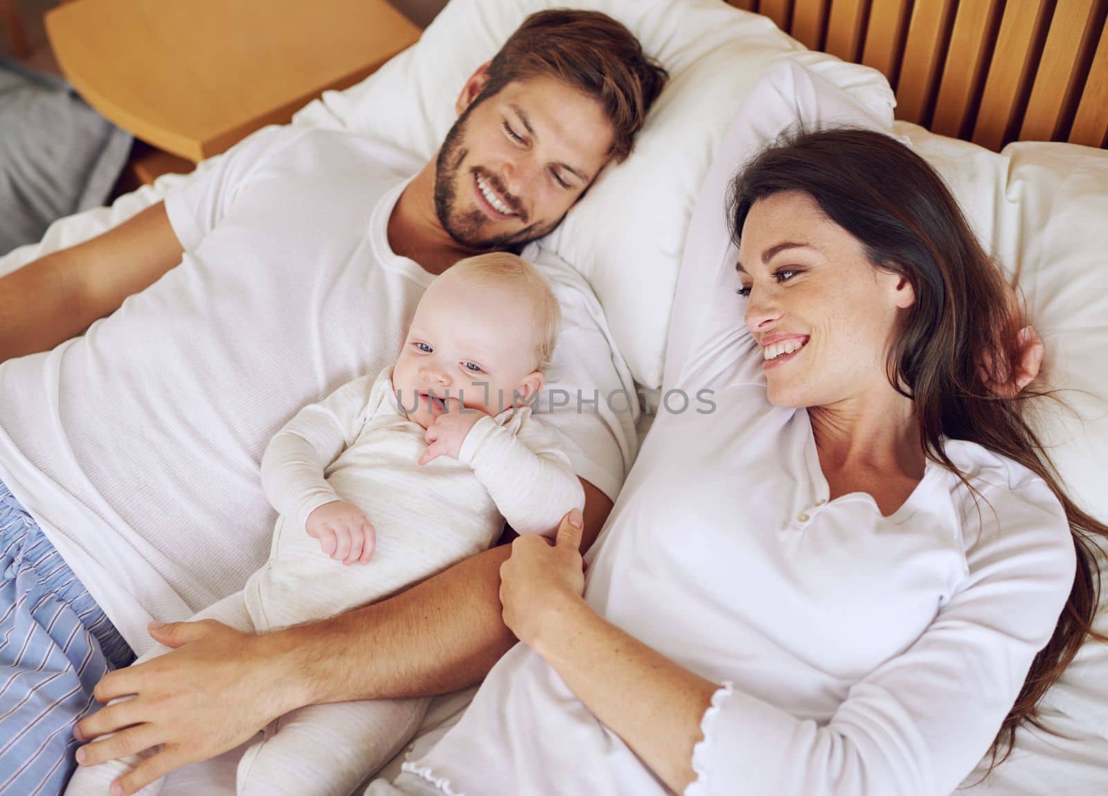 The perfect family. High angle shot of a young couple and their baby daughter in the bedroom. by YuriArcurs