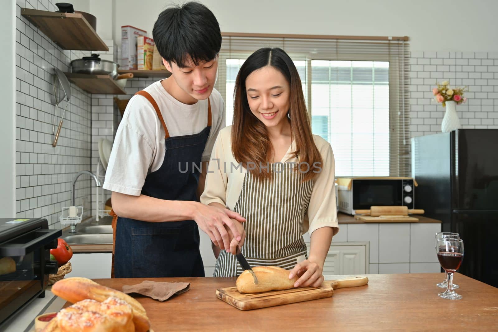 Romantic young couple preparing homemade pastry on wooden table in kitchen. Love, relationship, people and family.