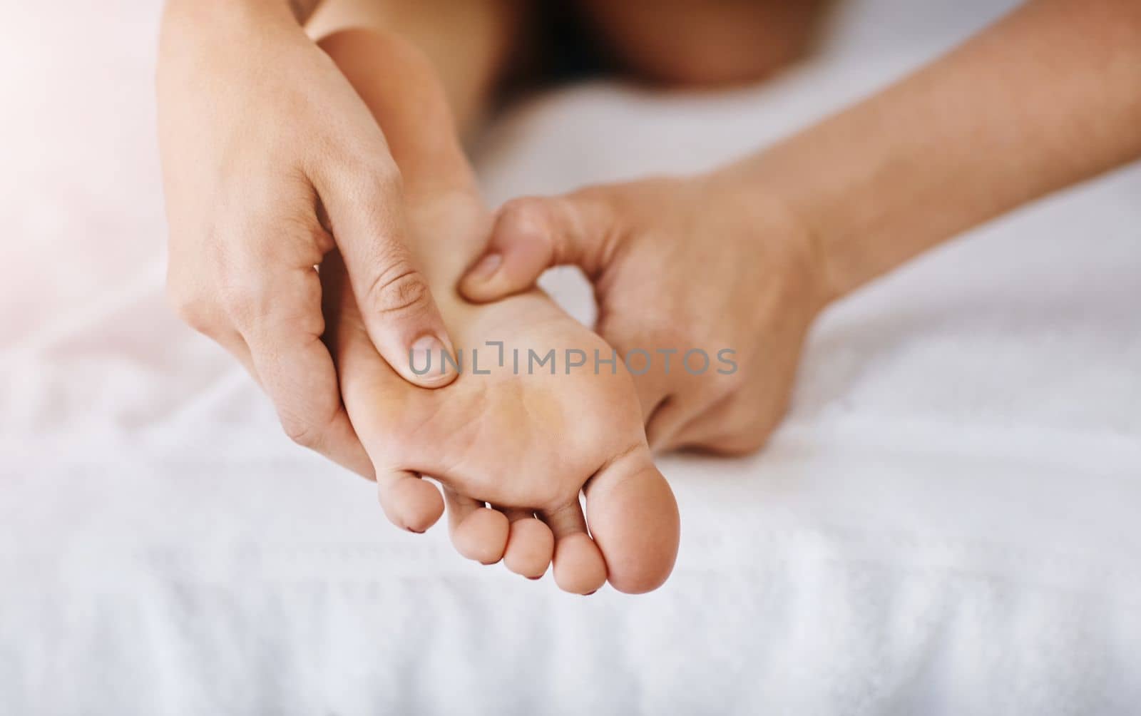 We all deserve a bit of downtime. a woman getting a foot massage at a beauty spa. by YuriArcurs