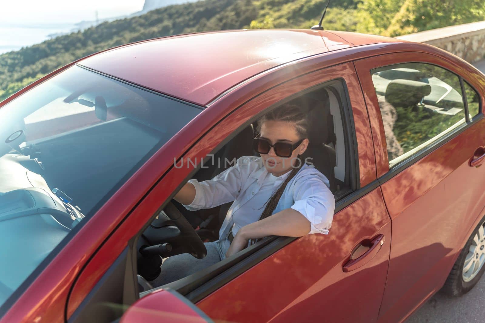 Woman driving a car. A lady in sunglasses takes the wheel of her by Matiunina