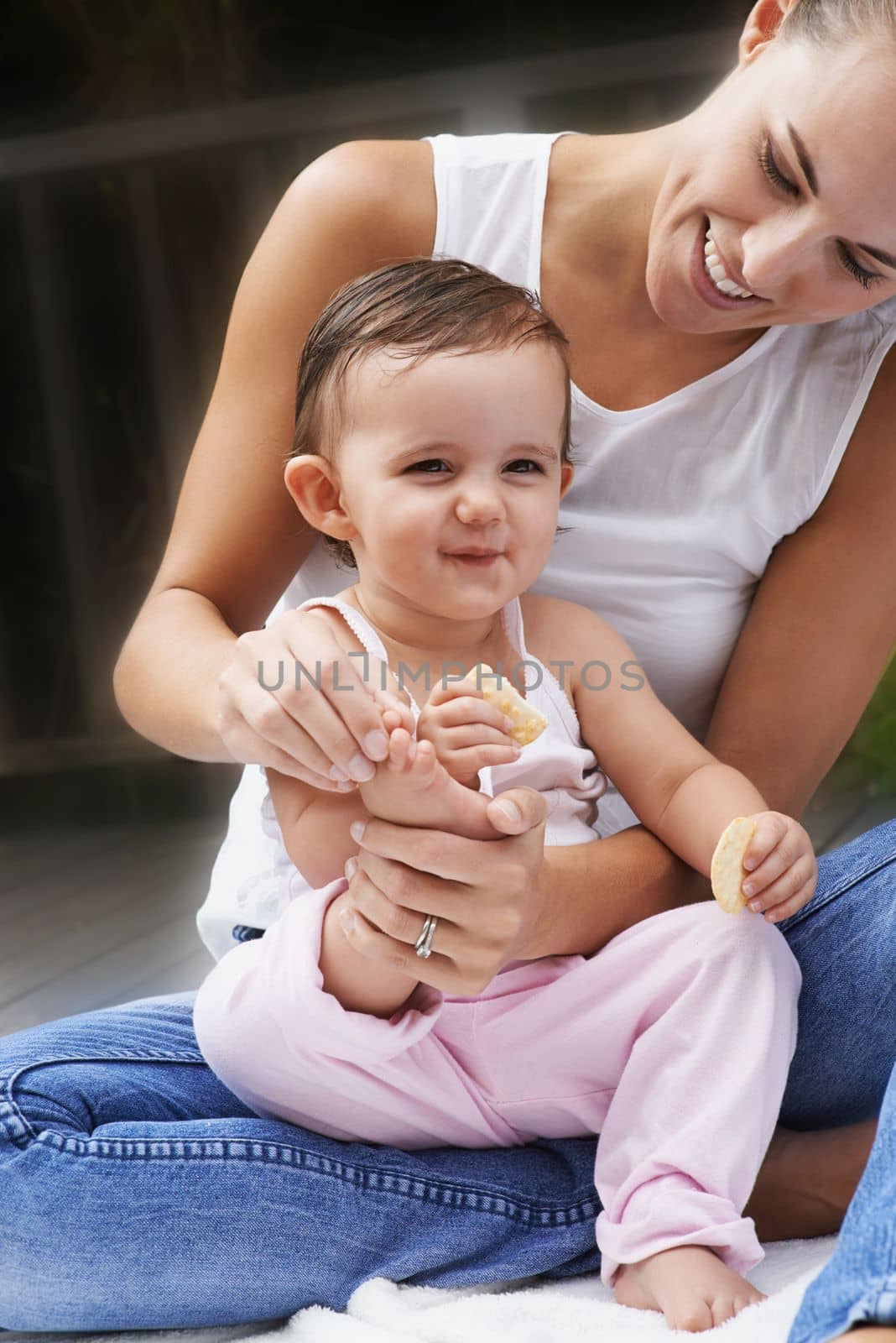 Motherly love. A young mother playing lovingly with her baby toes while they sit outside