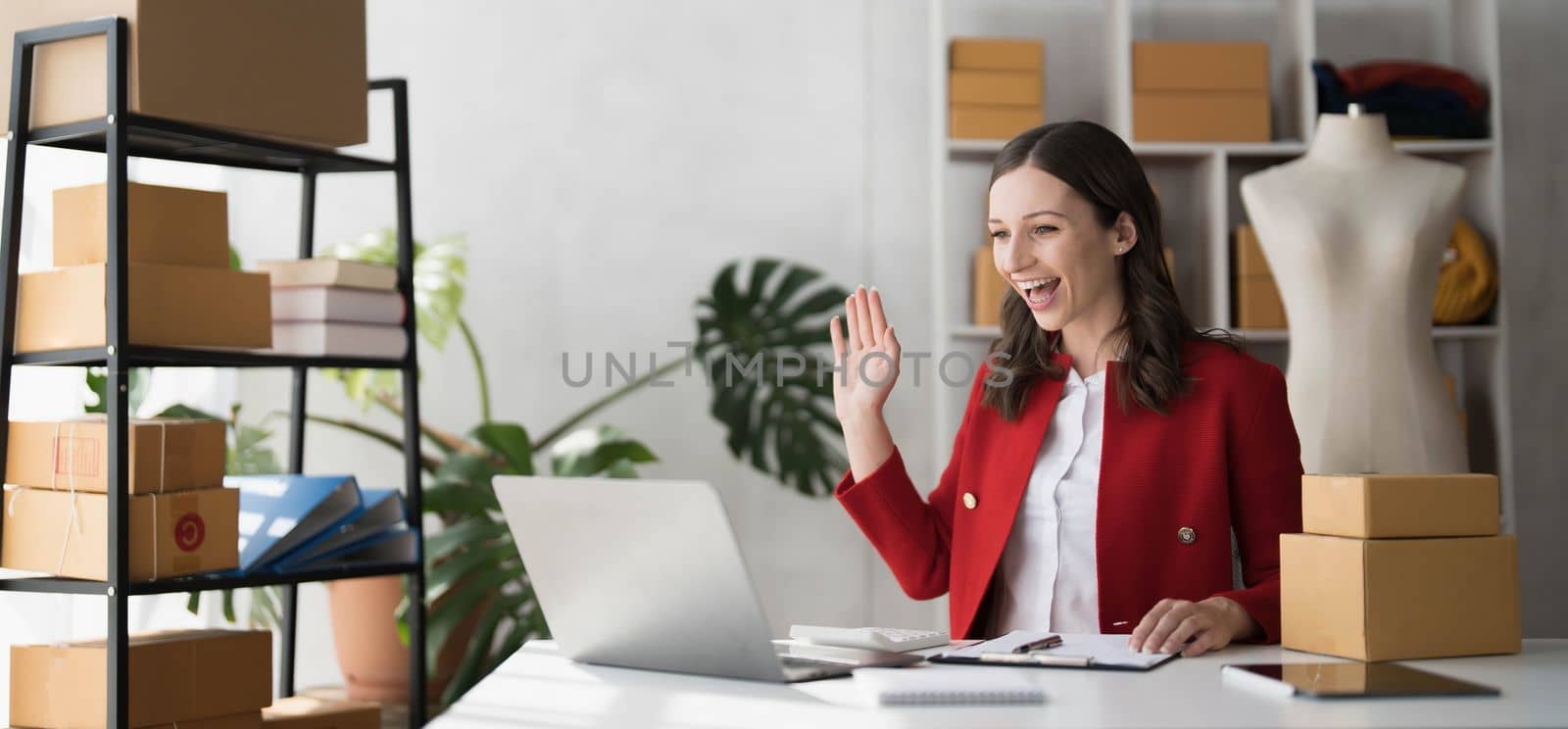 Smiling business owner working on laptop for livestreaming on social media, selling online...