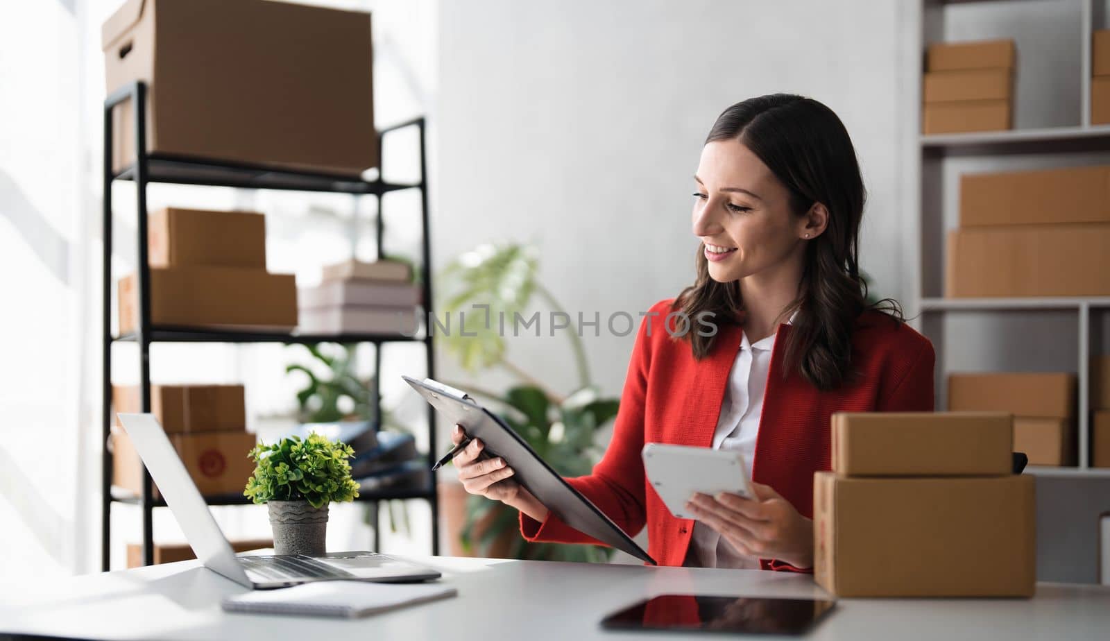 Entrepreneur using calculator with pencil in her hand, calculating financial expense at home office,online market packing box delivery,Startup successful small business owner, SME, concept..