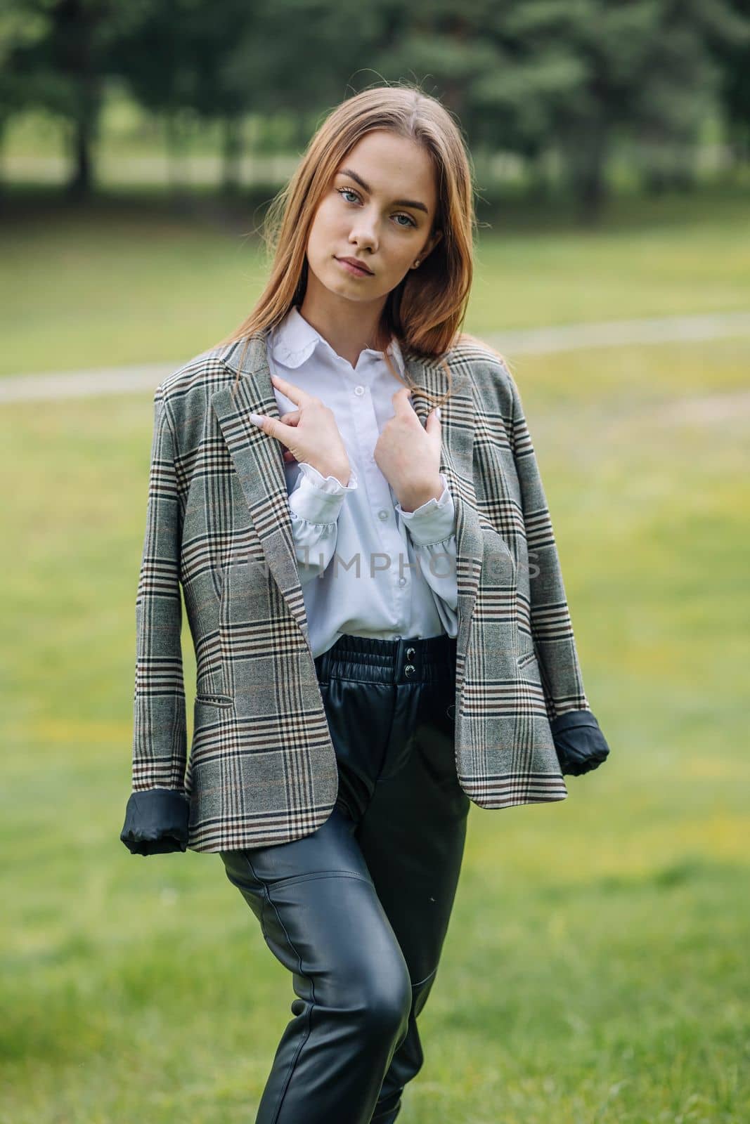 A young girl in a jacket poses in a park in the summer. by DovidPro