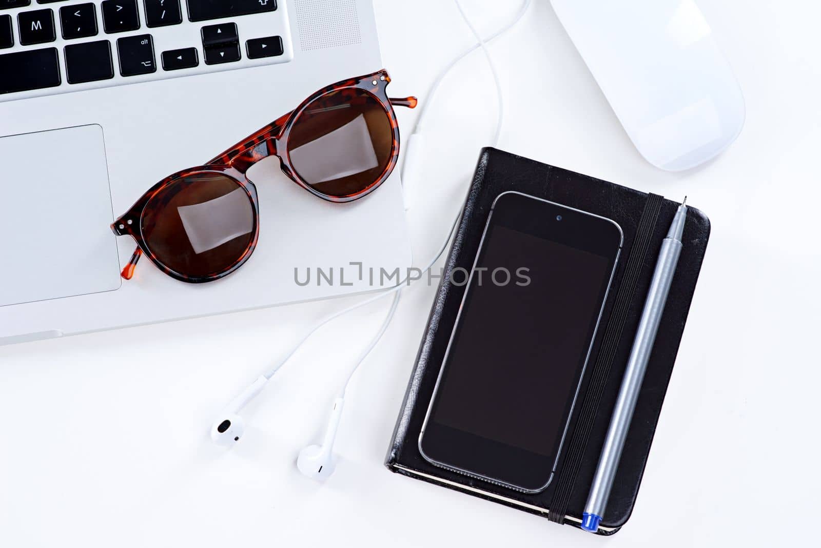 All you need for a productive day. a laptop, glasses, mouse and notebook on a table