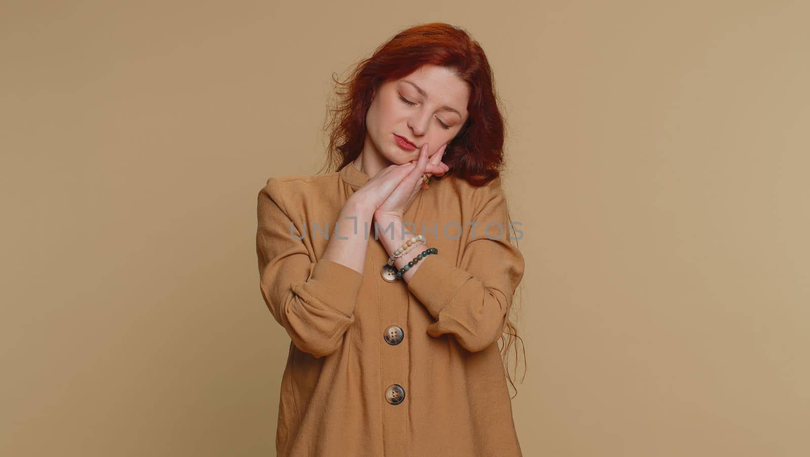 Tired redhead woman yawning, sleepy inattentive feeling somnolent lazy bored overworked gaping suffering from lack of sleep. Young exhausted ginger girl isolated alone on beige studio background